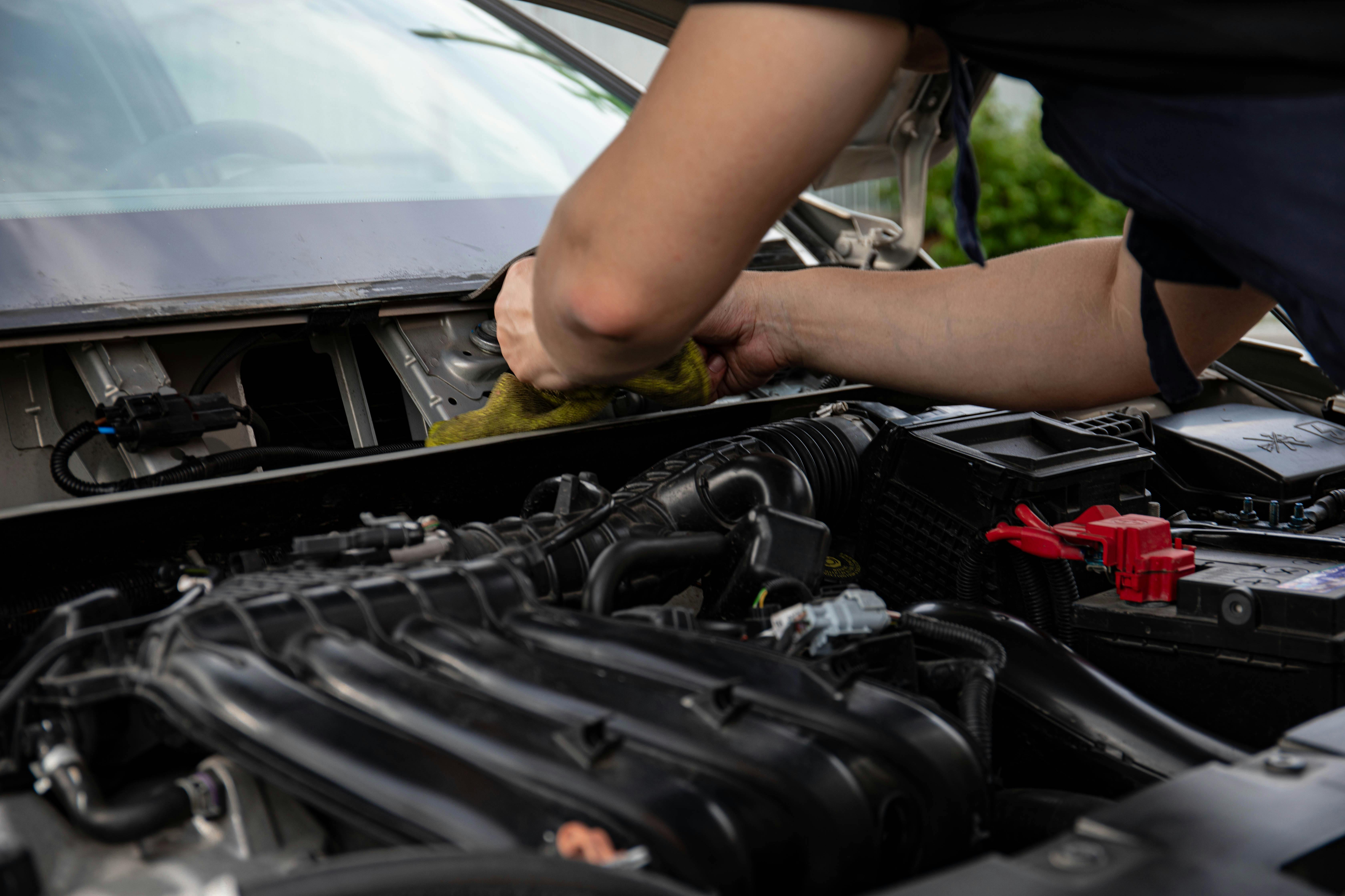 Vehicle mechanic cleaning engine bay during vehicle servicing and maintenance