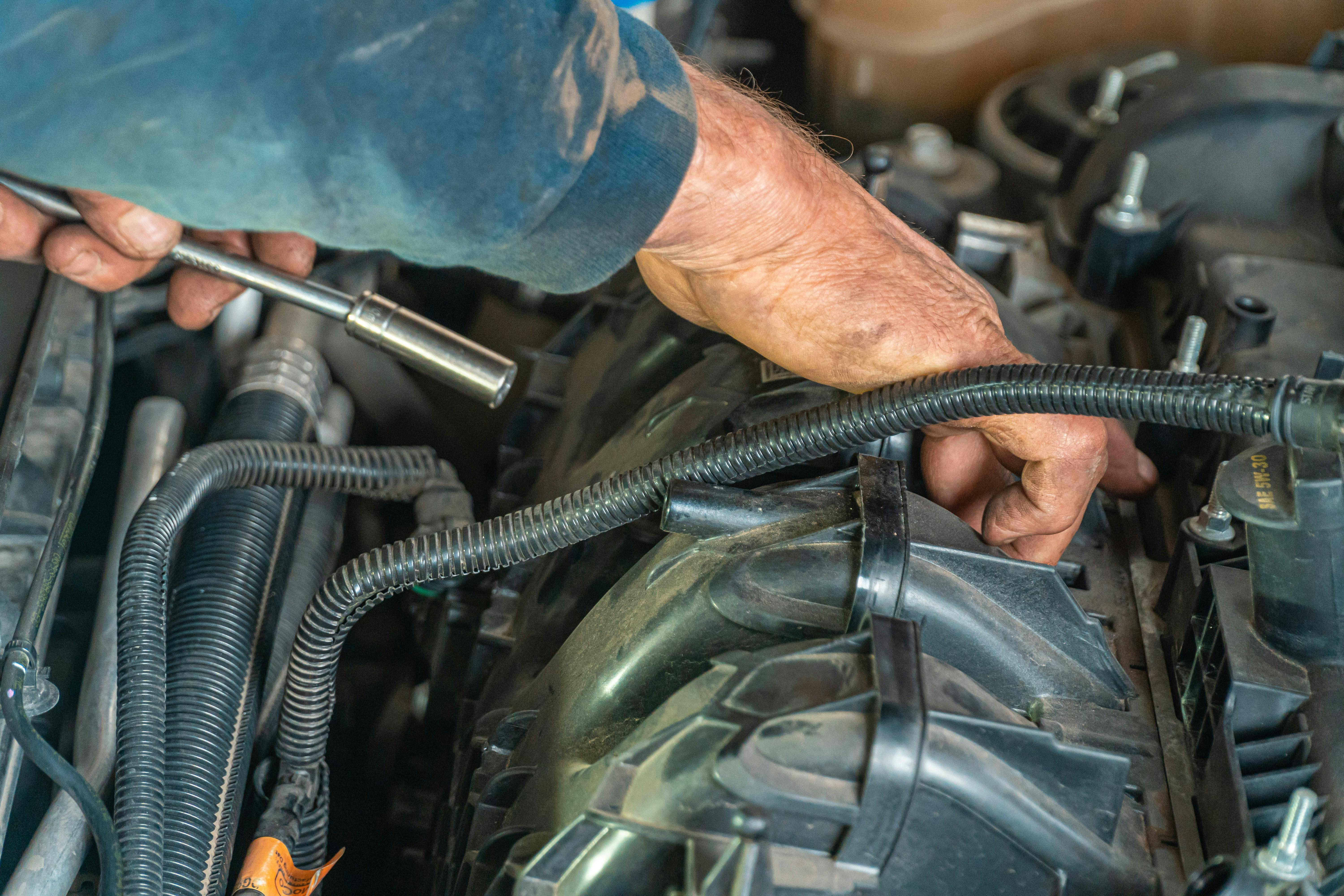 Auto mechanic repairing vehicle engine components with tools during engine repair service