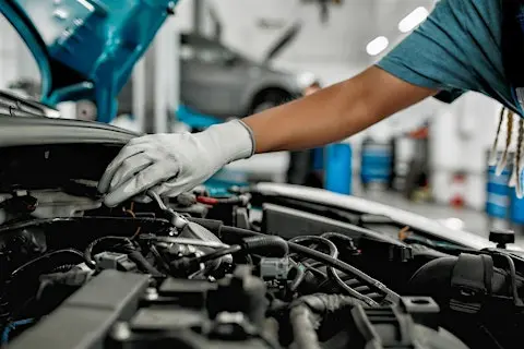 Auto Technician performing engine fitting London under car hood with gloves on