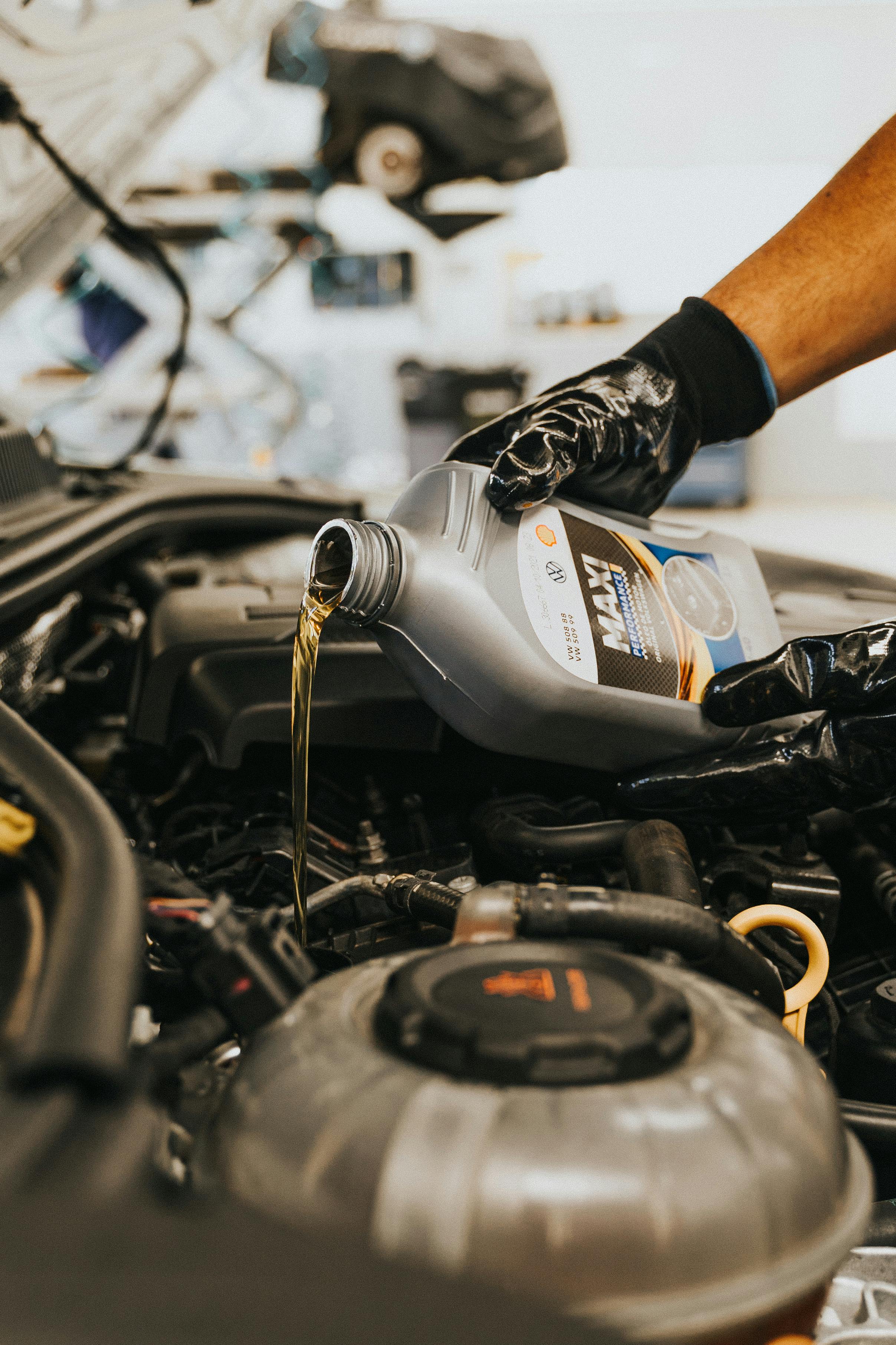 Vehicle Technician pouring fresh engine oil during car oil change service in Barking, London