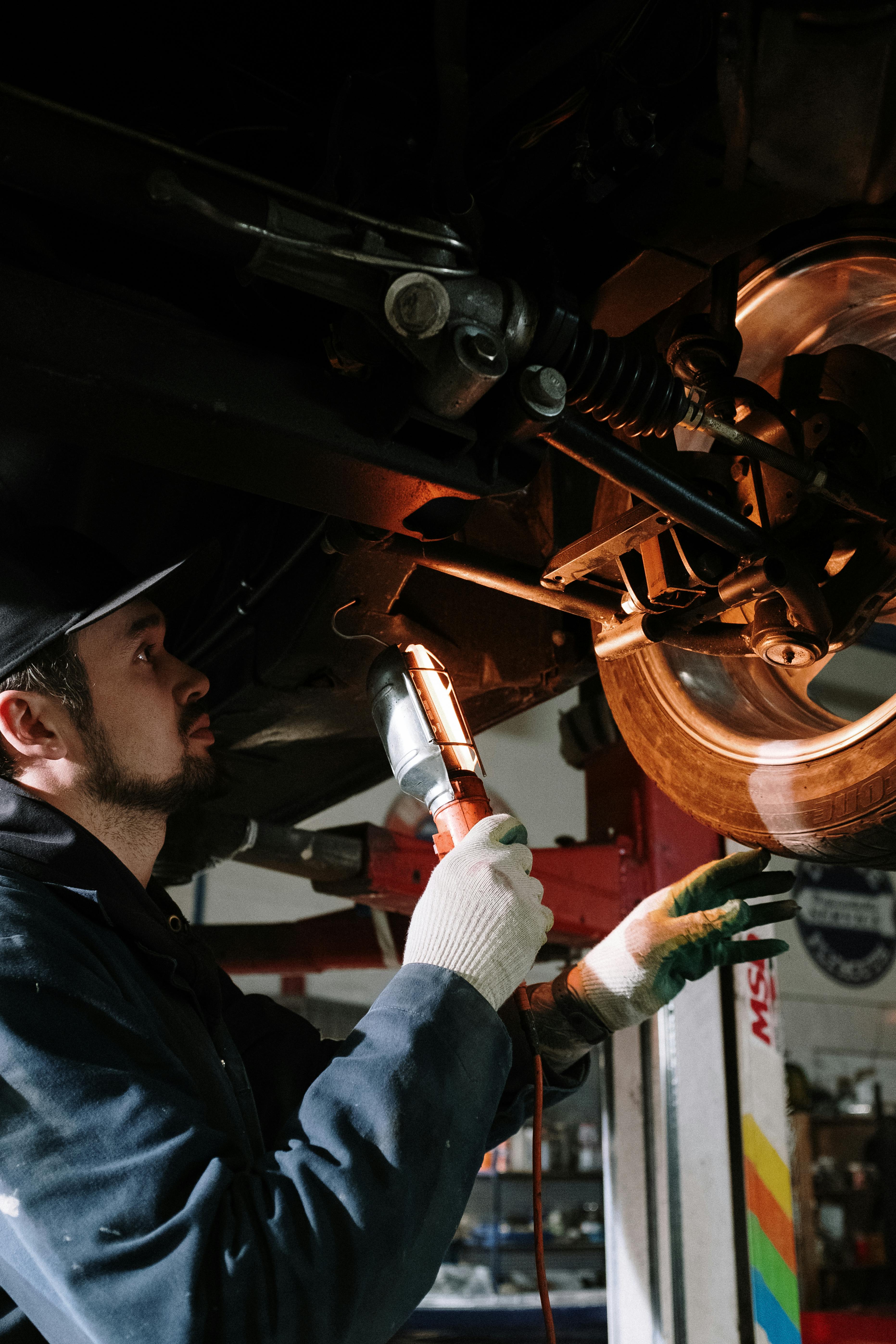 Technician checking brake components under car at BNS MOTORS, Barking, London.