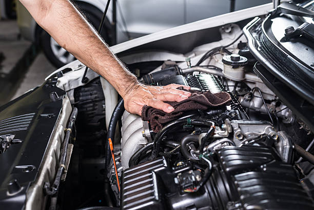Mechanic cleaning and inspecting vehicle engine at BNS Motors