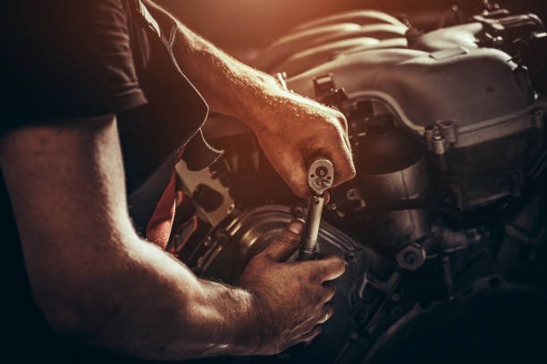 Auto mechanic fixing a vehicle engine with a socket wrench at BNS MOTORS LONDON
